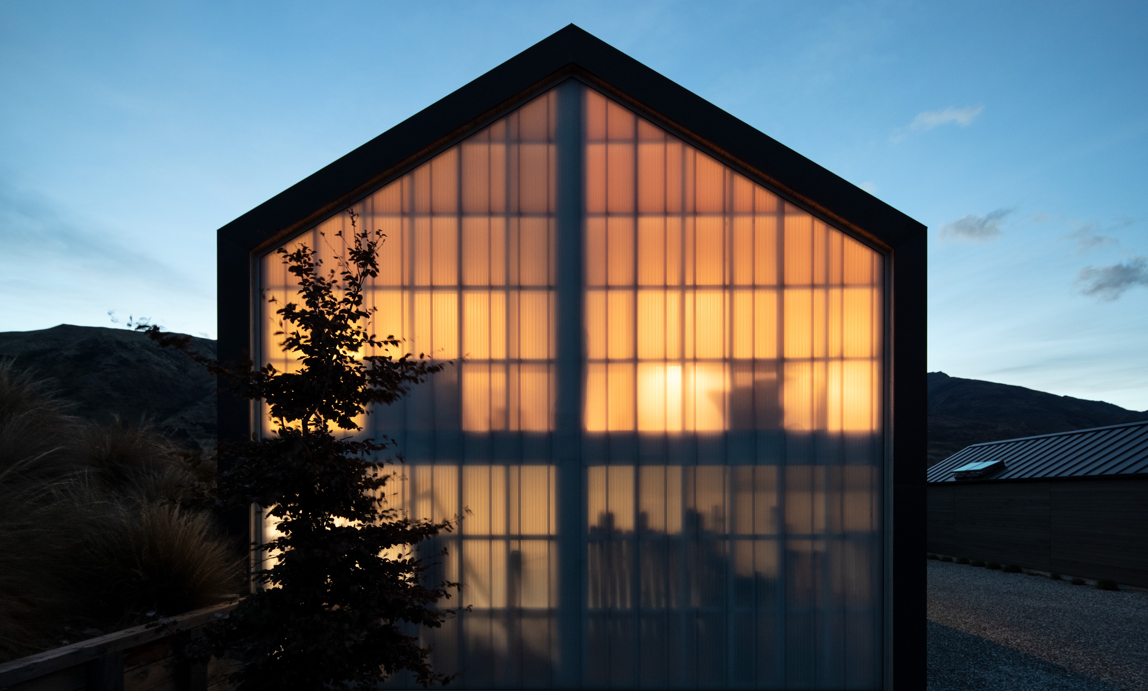 Exterior of Westmeadows Shed at night, with light shining through floor-to-sealing translucent polycarbonate