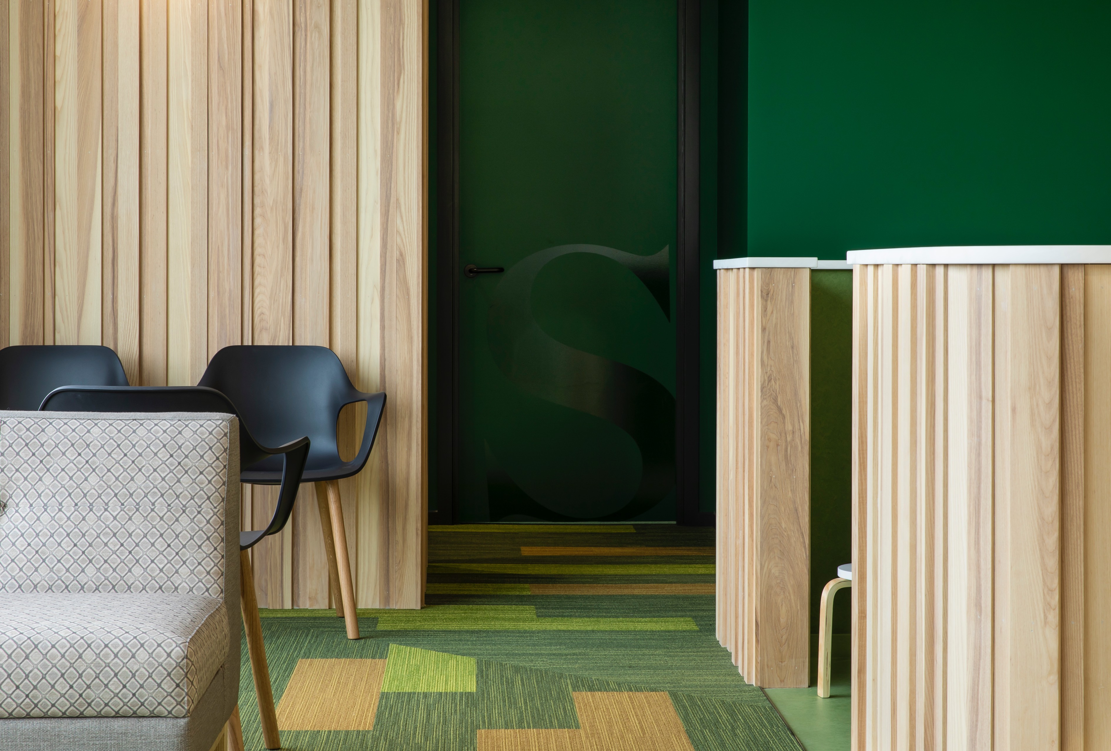 Waiting area with green palatte and wood finishes