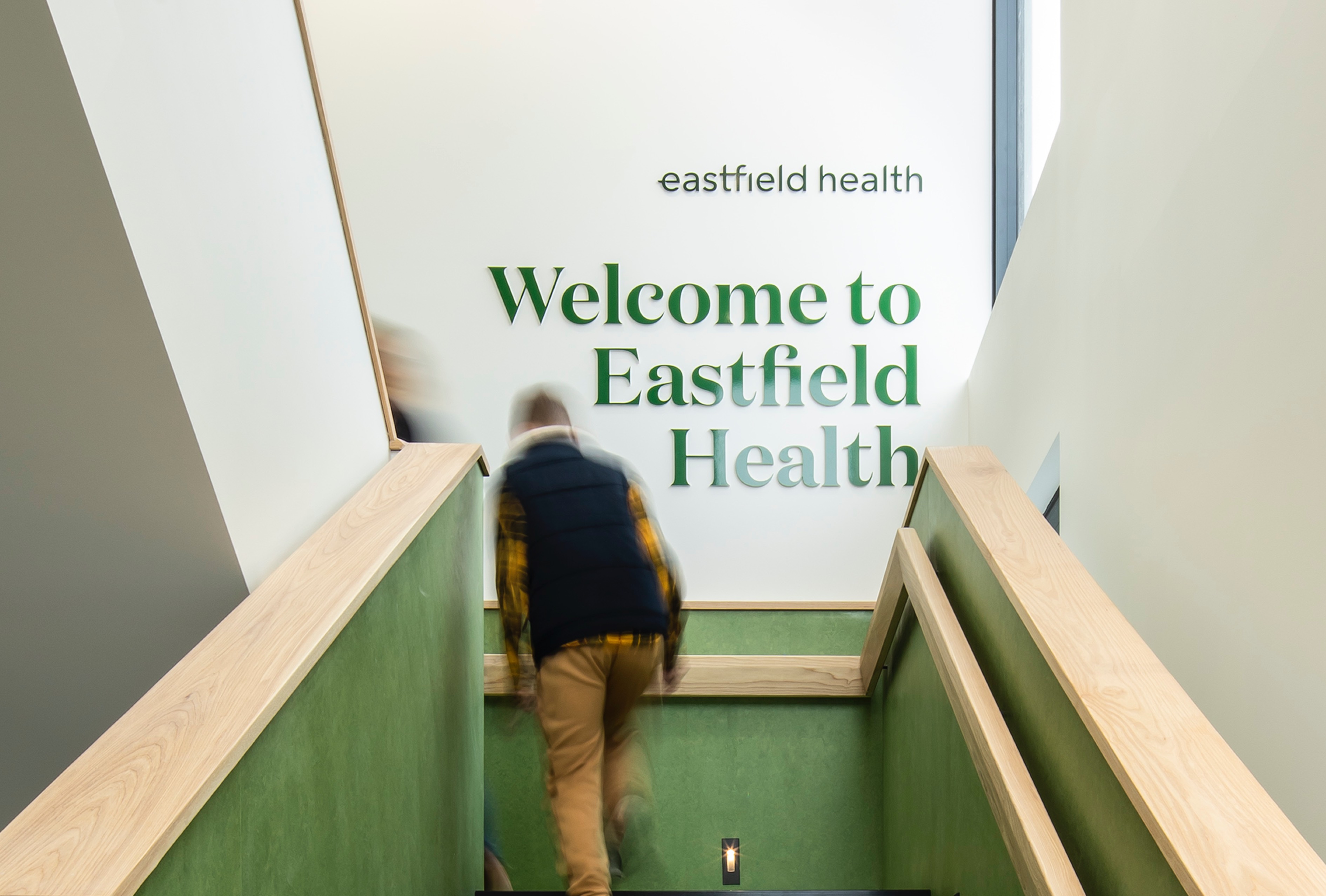 Man walking up green interior stairs at Eastfield Health