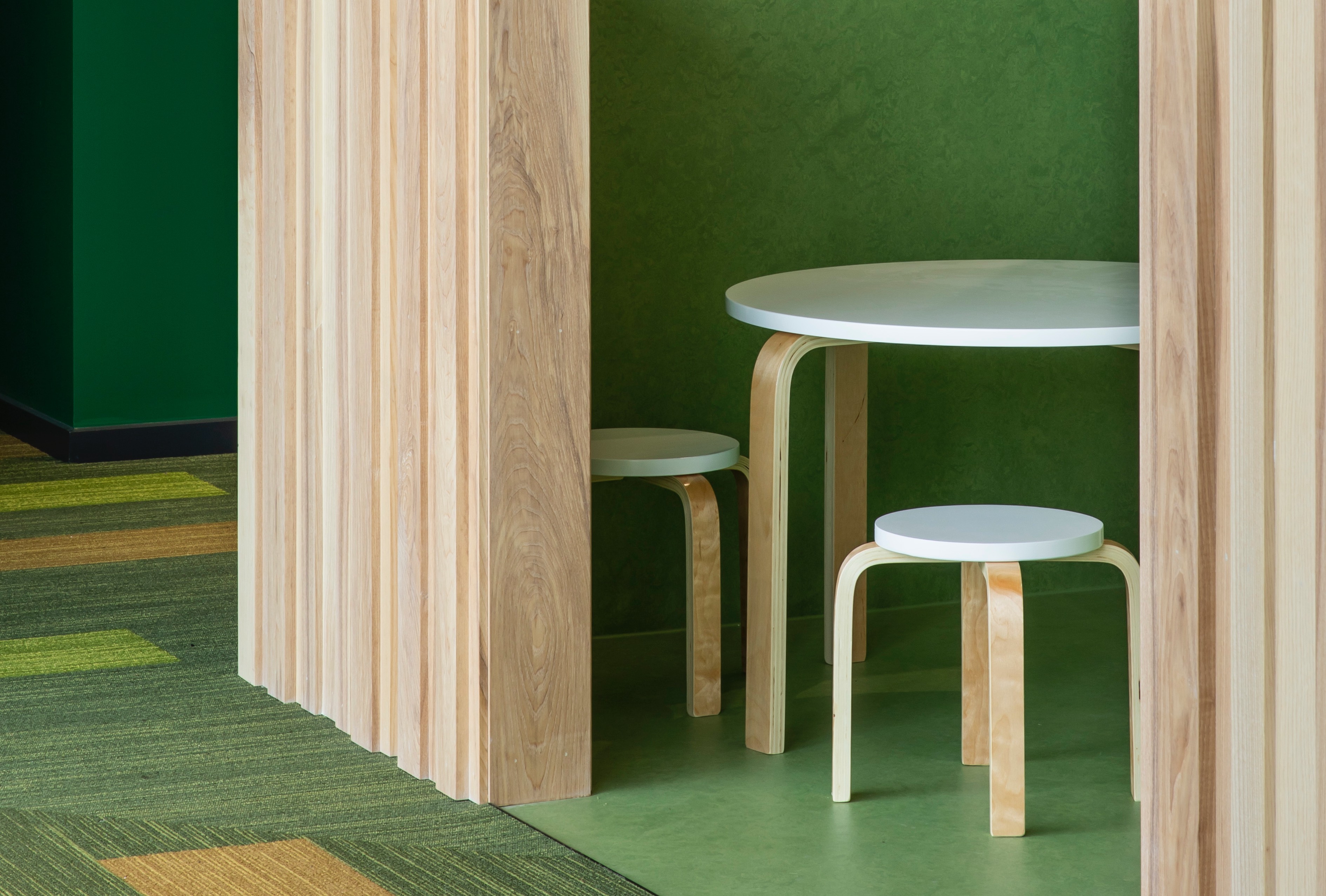Detail of childnres seating area depicting mid-century circular table and chairs with green palatte