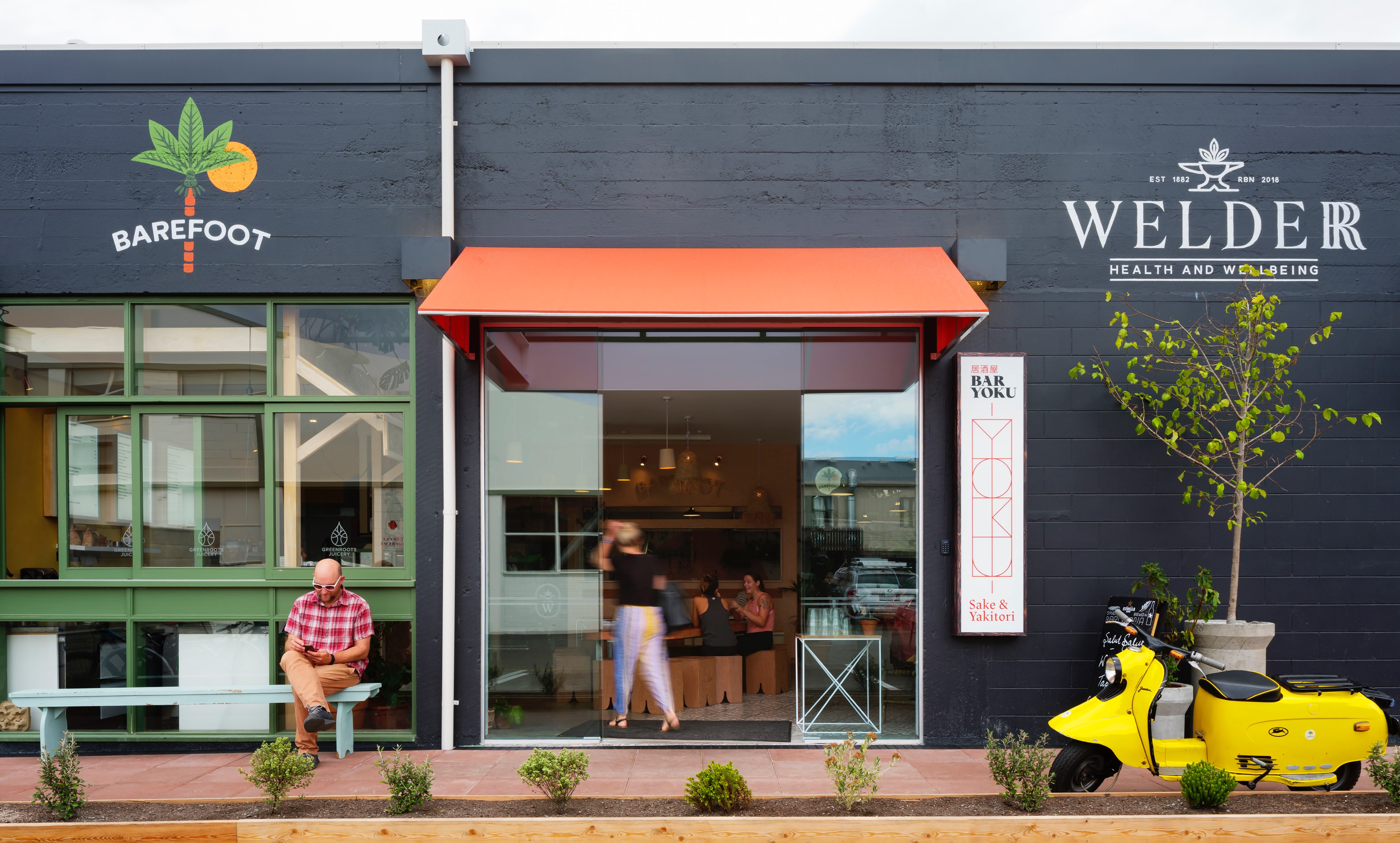 Exterior of The Welder with patrons inside at Greenroots Juicery