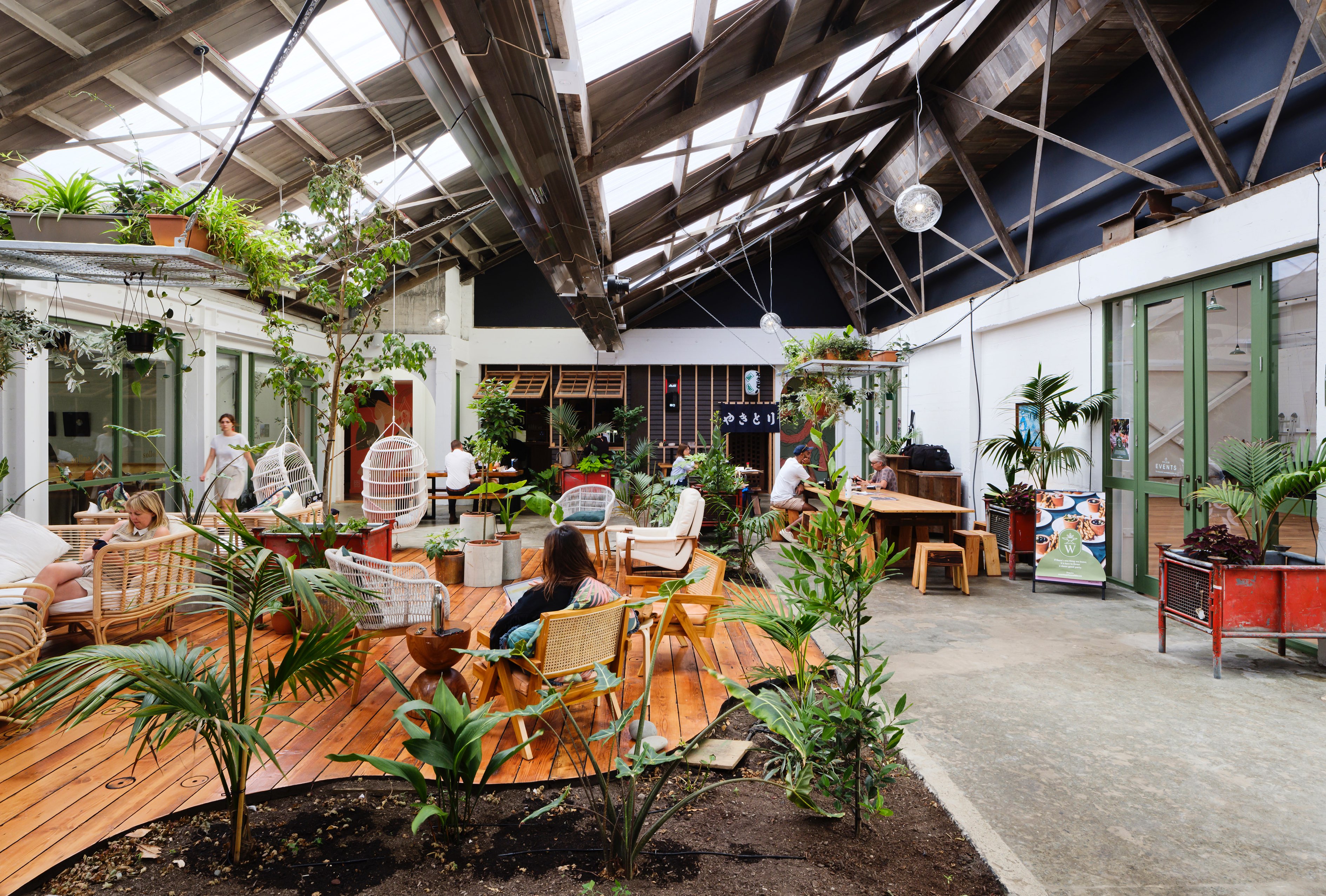Interior of an open-plan communal space with people sitting amongst interior greenery